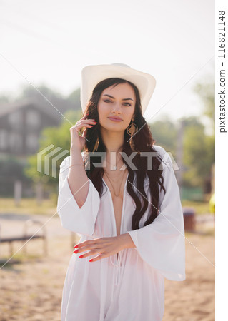 Portrait of a woman with long dark hair in a hat on the beach in summer 116821148
