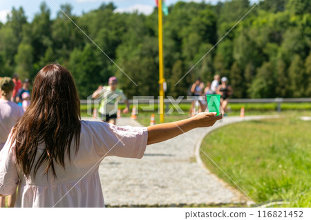 A volunteer in a white dress holds out a plastic cup of water to a triathlon runner. A volunteer in a white dress holds out a plastic cup of water to a triathlon runner. 116821452