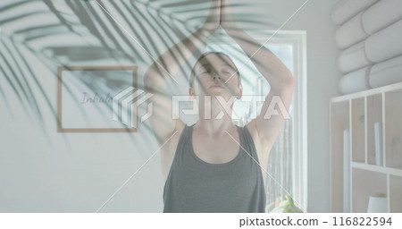 Image of green palm leaves over caucasian woman practicing yoga meditation in sunny room 116822594