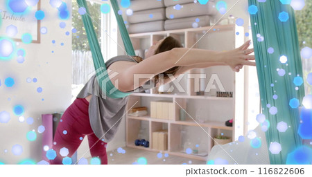 Image of blue and white light spots over caucasian woman practicing aerial yoga Image of blue and white light spots over caucasian woman practicing aerial yoga 116822606