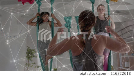 Image of network over diverse female instructor and teenager girls practicing aerial yoga 116822618