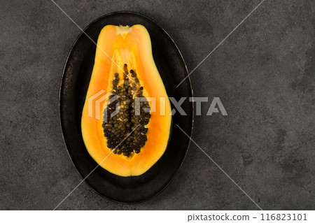 Half of a juicy ripe papaya on a black metal plate 116823101