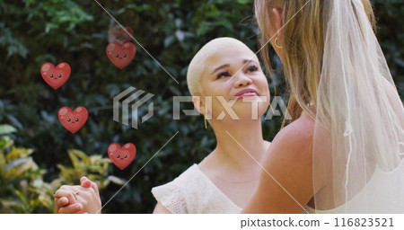 Image of hearts floating over diverse female married couple dancing 116823521