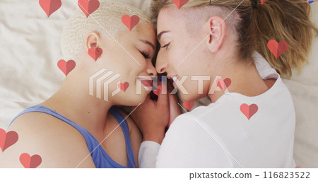 Image of hearts floating over diverse female couple embracing 116823522
