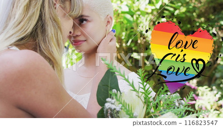 Image of rainbow heart with love is love text over diverse female married couple embracing 116823547