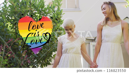 Image of rainbow heart with love is love text over diverse female married couple holding hands Image of rainbow heart with love is love text over diverse female married couple holding hands 116823550