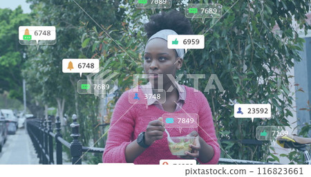 Image of media notifications over african american woman eating in city street Image of media notifications over african american woman eating in city street 116823661