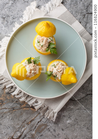 Salad of tuna, eggs, cucumber and cream in fresh lemons close-up in a plat. Vertical top view Salad of tuna, eggs, cucumber and cream in fresh lemons close-up in a plat. Vertical top view 116824900