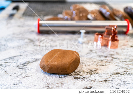 In a contemporary white kitchen, gingerbread cookie dough is skillfully rolled out, setting the stage for a delightful holiday treat. 116824992