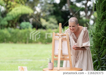 Woman Painting Outdoors on a Sunny Day with Easel and Canvas in a Green Park Setting Woman Painting Outdoors on a Sunny Day with Easel and Canvas in a Green Park Setting 116826373