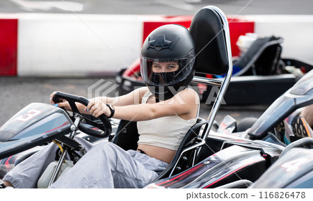 Portrait Of Young Girl In Protective Helmet In Racing Go-Kart On A Track Portrait Of Young Girl In Protective Helmet In Racing Go-Kart On A Track 116826478