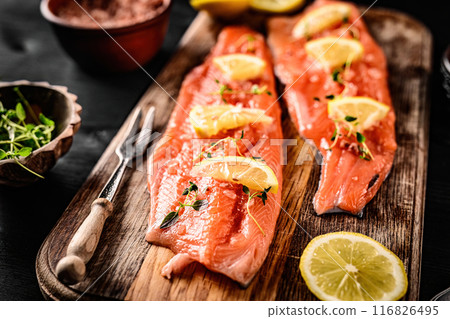 Fresh trout salmon filet with rosemary and lemons on wooden board ready served with knife. Omega orange fish with citrus fruit for healthy nutrition 116826495