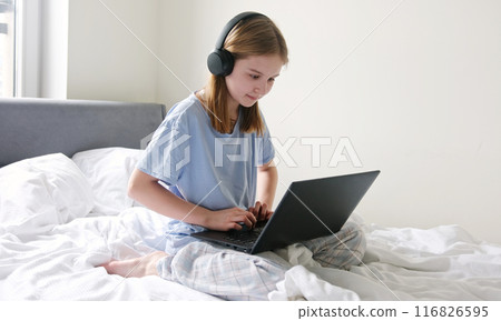 Sweet Young Girl Browsing The Internet While Sitting On A Large Bed In Her Bedroom 116826595