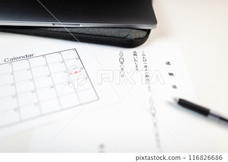 A resignation letter, a schedule book with the resignation date written on it, and business tools placed on a white desk 116826686