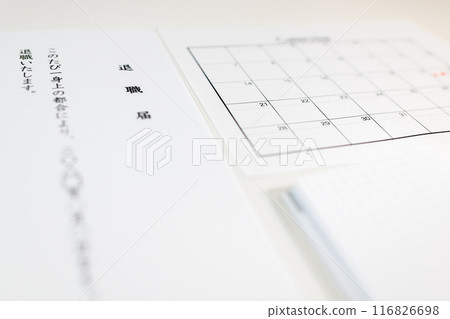 一本日程表和記事本，上面寫著辭職信的文本和退休日期，寫在白色桌子上 116826698