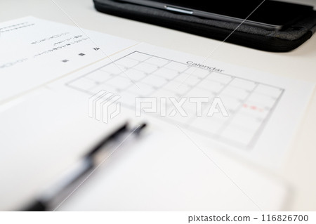 A resignation letter, a schedule book with the resignation date written on it, and business items placed on a white desk A resignation letter, a schedule book with the resignation date written on it, and business items placed on a white desk 116826700