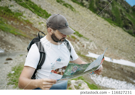 tourist man hiking in mountains looking at the map for direction tourist man hiking in mountains looking at the map for direction 116827231