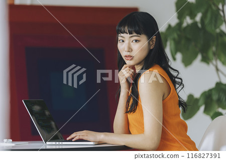 一位年輕女子在筆記型電腦上看著相機工作的肖像 一位年輕女子在筆記型電腦上看著相機工作的肖像 116827391