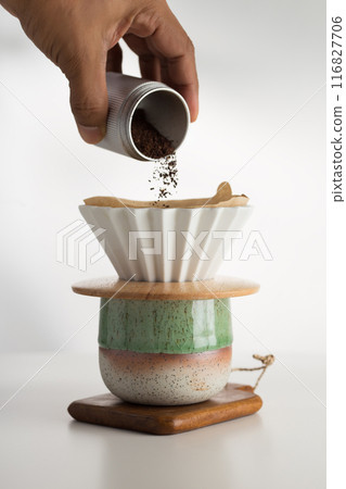 Hand pours coffee grounds for precision brewing. 116827706
