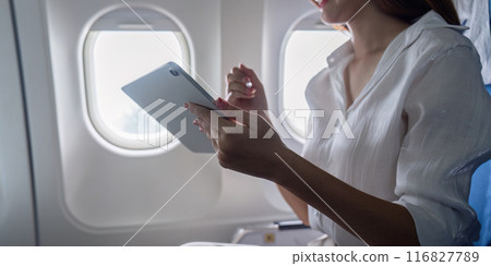 Businesswoman Using Tablet on Airplane During Business Trip for Work and Communication Businesswoman Using Tablet on Airplane During Business Trip for Work and Communication 116827789