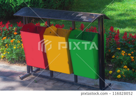 A public park with a walking area with a flower bed and garbage bins painted red, yellow, green, reminiscent of traffic lights. Improvement of urban public places A public park with a walking area with a flower bed and garbage bins painted red, yellow, green, reminiscent of traffic lights. Improvement of urban public places 116828052