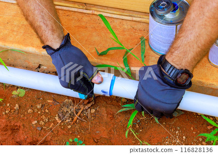 Contractor installing glues plastic PVC pipes for laying water distribution system 116828136
