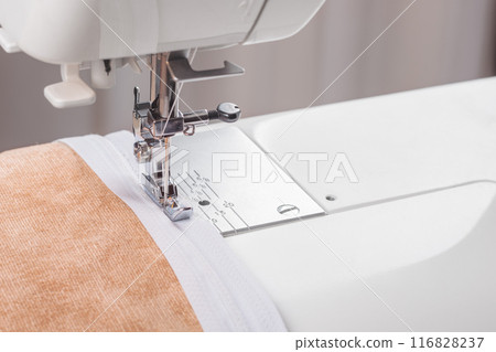 Modern sewing machine special presser foot with beige fabric and zipper, closeup 116828237