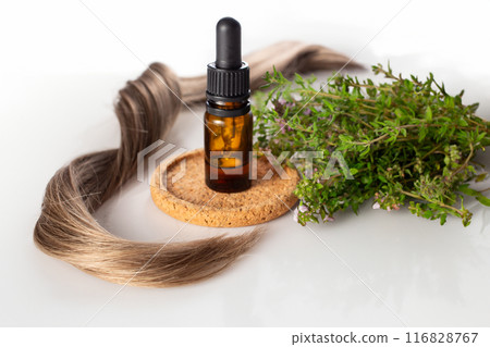 Fresh thyme, essential oil and hair isolated on the white background. Hair treatment concept. Close up Fresh thyme, essential oil and hair isolated on the white background. Hair treatment concept. Close up 116828767