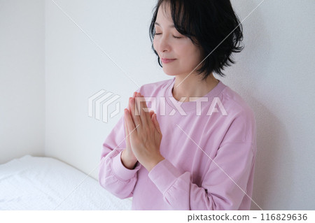 Middle-aged woman meditating to calm her mind Middle-aged woman meditating to calm her mind 116829636