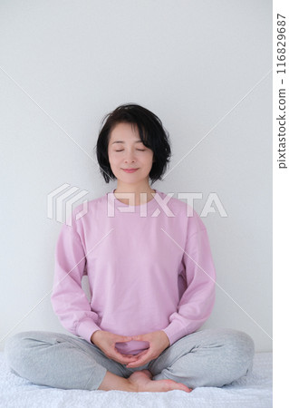 Middle-aged woman meditating to calm her mind 116829687