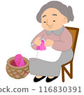 Old woman sits on a wooden chair, crocheting fabric. 116830391
