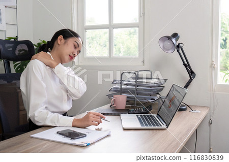 Young Woman Experiencing Neck Pain While Working at Desk in Modern Office Setting 116830839