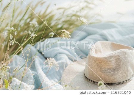 Cream straw hat resting on blue fabric among summer wildflowers. Generative AI 116831040