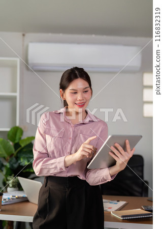 Professional Businesswoman Using Tablet in Modern Office Setting with Plants and Documents Professional Businesswoman Using Tablet in Modern Office Setting with Plants and Documents 116832319
