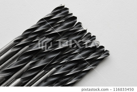 Tightly fitted to each other black metal drills on white plastic sheet 116833450