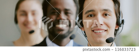 Website header of biracial team of operators wearing black headphones with microphone, thy looking at camera and smiling 116833723
