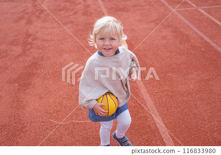 The child is playing with the ball on a playground The child is playing with the ball on a playground 116833980