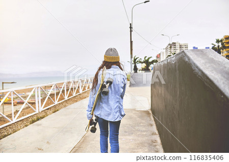 Girl having fun riding skateboards at skate park, Portrait of smiling young female skateboarder holding her skateboard. Recreational Activity Concept. Girl having fun riding skateboards at skate park, Portrait of smiling young female skateboarder holding her skateboard. Recreational Activity Concept. 116835406