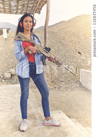 Woman empowered shooter aiming assault rifle at target. Selective Focus 116835458