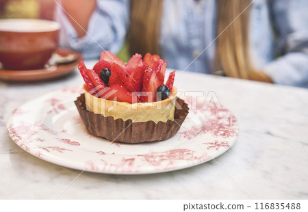 Young woman tasting strawberry-topped cake, Selective focus. Young woman tasting strawberry-topped cake, Selective focus. 116835488