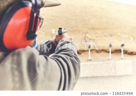 Man with hand gun aiming at shooting range and releasing stress. Selective Focus 116835494