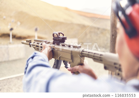 Woman empowered shooter aiming assault rifle at target. Selective Focus 116835553