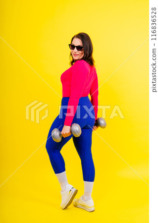 Full length isolated studio portrait of a beautiful chubby woman doing exercises with dumbbells. Full length isolated studio portrait of a beautiful chubby woman doing exercises with dumbbells. 116836528