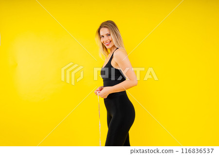 A weight loss and healthy lifestyle concept. Smiling slim woman measuring her waist with tape A weight loss and healthy lifestyle concept. Smiling slim woman measuring her waist with tape 116836537