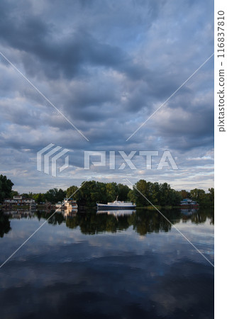 Two old boats on the river bank. Early morning. In the background, the sky is covered with clouds. 116837810
