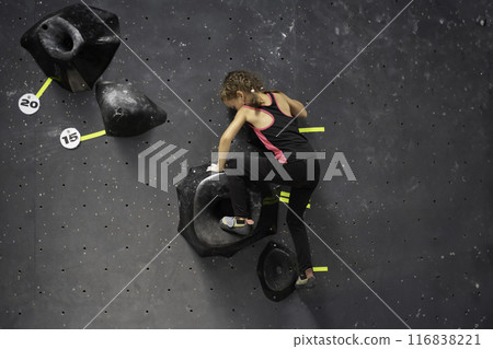 Little girl trained climbs artificial wall at Little girl trained climbs artificial wall at 116838221