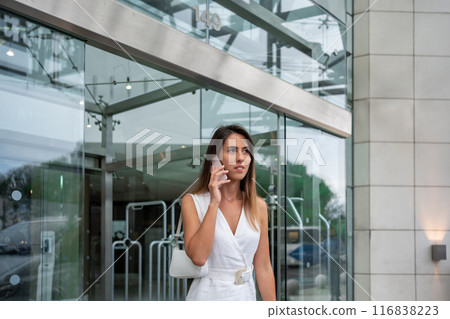 Businesswoman talking on smartphone near modern Businesswoman talking on smartphone near modern 116838223
