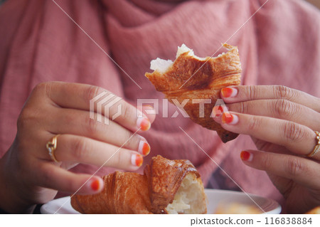 closeup of hand breaking a croissant bun  116838884