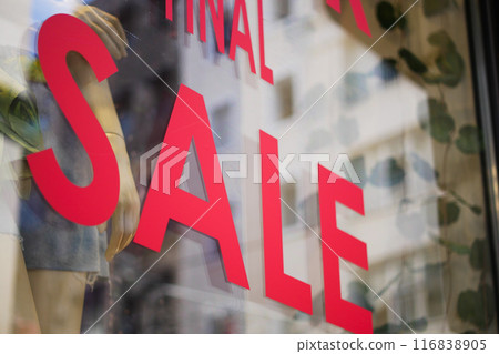 Large red Sale text letters on a glass wall obstruct a view inside the popular fashion store Large red Sale text letters on a glass wall obstruct a view inside the popular fashion store 116838905