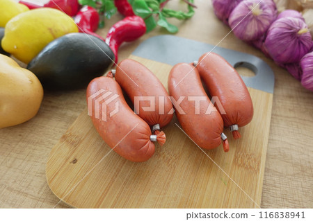 Fresh sausages with vegetables on a cutting board, perfect for a culinary experience in the kitchen 116838941